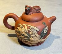 Side view showing phoenix relief, handle and tiger finial