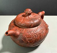 Side view showing body, spout, relief design