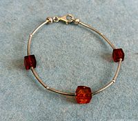 Full view of sterling silver bracelet showing three amber-tone cube beads and tubular links