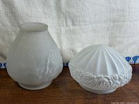 Both frosted glass lamp shades side by side on table