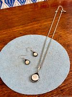Full view of pendant necklace and matching earrings on felt background