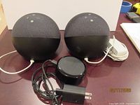 Front view showing two spherical 4th Gen Echo Dots and one 2nd Gen Echo Dot with power adapters