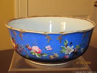 Side view showing cobalt blue exterior, floral decoration, white interior and scalloped gilt rim