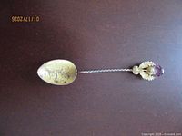 Full view of spoon showing gold wash bowl with carriage design, twisted stem, and thistle finial