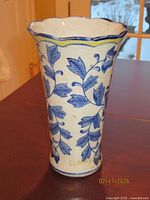 Front view of tall ceramic vase with blue floral pattern and yellow-trimmed scalloped rim