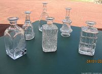 Group of six crystal and cut glass decanters on table