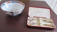 Serving bowl beside open case containing two salad spoons