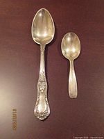 Two spoons side by side on dark surface