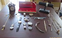 Group view of all watches, pendant watches and alarm clock on table