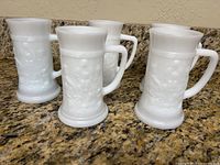 Group of five white milk glass steins on countertop
