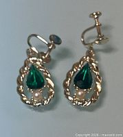 Front view of both earrings showing emerald green rhinestones, faux pearls, and screw-back fittings