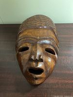 Front view of hardwood mask showing facial features and open mouth