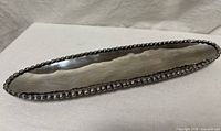 Full view of elongated metal mezuzah with beaded edge