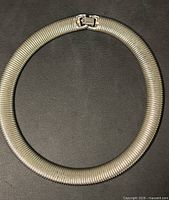 Full view of circular snake chain collar necklace laid flat