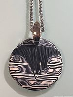 Front view of round black and white swirl pendant with silver-tone bail