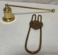 Skirt lifter lying flat next to candle snuffer showing full forms