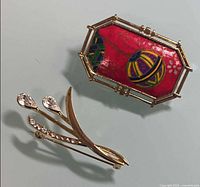 Both brooches front view showing designs and settings