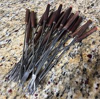 Group of fondue forks showing stainless prongs and wood handles