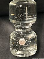 Full view of glass paperweight showing hourglass shape and controlled bubbles