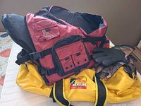 Red Bass Pro Shops life jacket, yellow duffel and gloves overview
