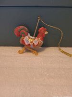 Left profile of rooster ornament showing saddle and hanging cord