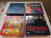 Four trivia games: Trivial Pursuit Master Game Genus Edition, Trivial Pursuit Genius IV, Simpsons Ultimate Trivia Game tin, Sopranos Trivia Game tin