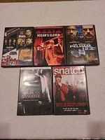 Five DVD cases visible: 4 Film Favorites case (Goodfellas / The Departed), Ocean's Eleven, The Taking of Pelham 123, American Gangster, Snatch