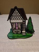front view of stained glass house figurine showing door, windows, tree and base