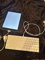 iPad 2 with keyboard, charge cable and USB adapter displayed together