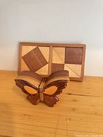 Butterfly puzzle box in front of rectangular shape puzzle showing geometric inlay