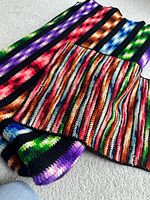 Large and small multicolored striped crocheted afghans displayed on floor