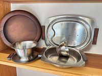 Group shot of all five stainless and wood serving pieces on shelf