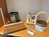All items: wood/steel napkin holder, Wizard of Clay stoneware basket with rattan handle, black leaf-panel lantern, stack of four butterfly coasters