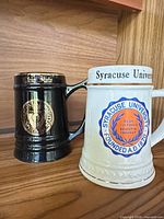 Black Ohio State and white Syracuse University steins side by side front view