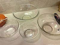 Four clear Pyrex bowls nested side by side on countertop