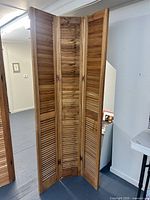 Full view of 3-panel wood shutter divider standing upright