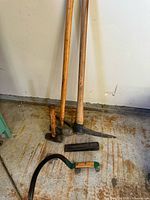 Group view of three long-handled tools, short sledge, wedge and sickle