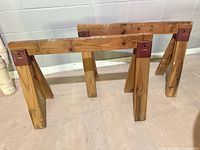 Both wooden saw horses standing on floor against wall