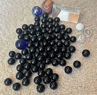 Group of black marbles, colored marbles, rubber ball, glass chips and prism on carpet