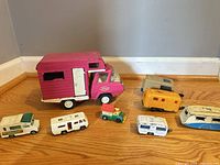 Group shot of all eight camper toys including large pink truck and seven small trailers