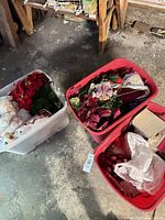 Three plastic tubs with poinsettias, faux greenery, ornaments and boxed decorations