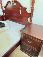 Nightstand beside bed showing two drawers and finish