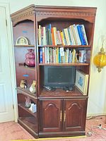 Full view of corner entertainment center loaded with books, TV, decor