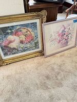 Both framed prints standing on carpeted floor