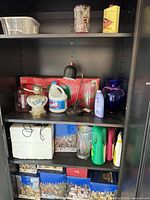 Cabinet shelves with glassware, cleaning bottles, lamps, holiday village boxes