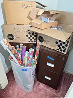 View of file cabinet, wrapping paper in tub, cardboard boxes stacked above