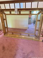 Full view of rectangular gold ornate mirror leaning against railing