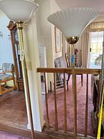 Full view of both brass torchiere lamps with distinct glass shades