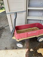 Red Radio Flyer wagon in front of beige plastic storage cabinet