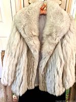 Front view white fur coat on hanger, showing texture and length